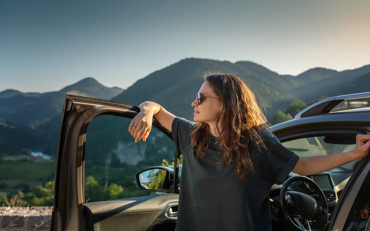 Woman standing by open car